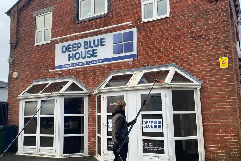 Roof Cleaning in Fareham Dall Cleaning Company operative using reach and wash system to clean windows at Deep Blue House commercial office in Fareham